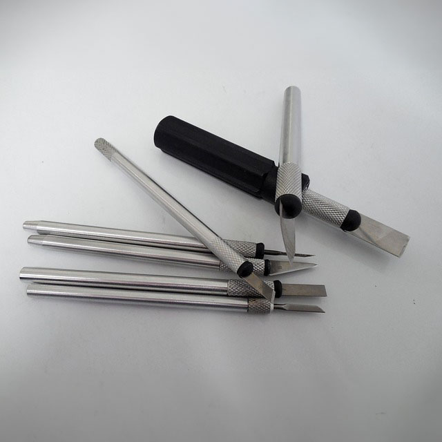 Offene Scalpellklingen mit Scalpellgriffen durcheinander auf einem grauen Hintergrund gelegt.jpg